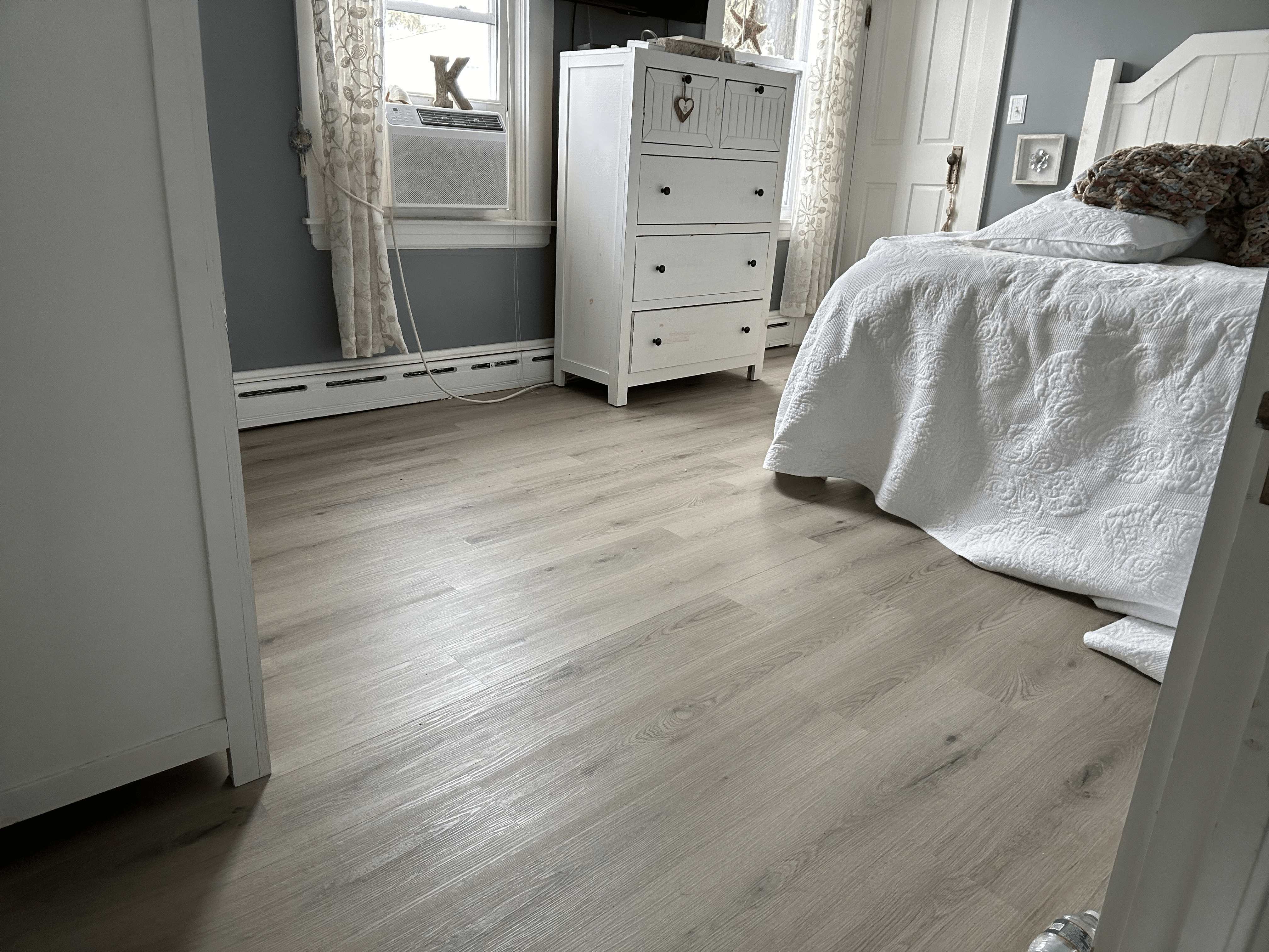 Light gray luxury vinyl plank flooring in a bright bedroom