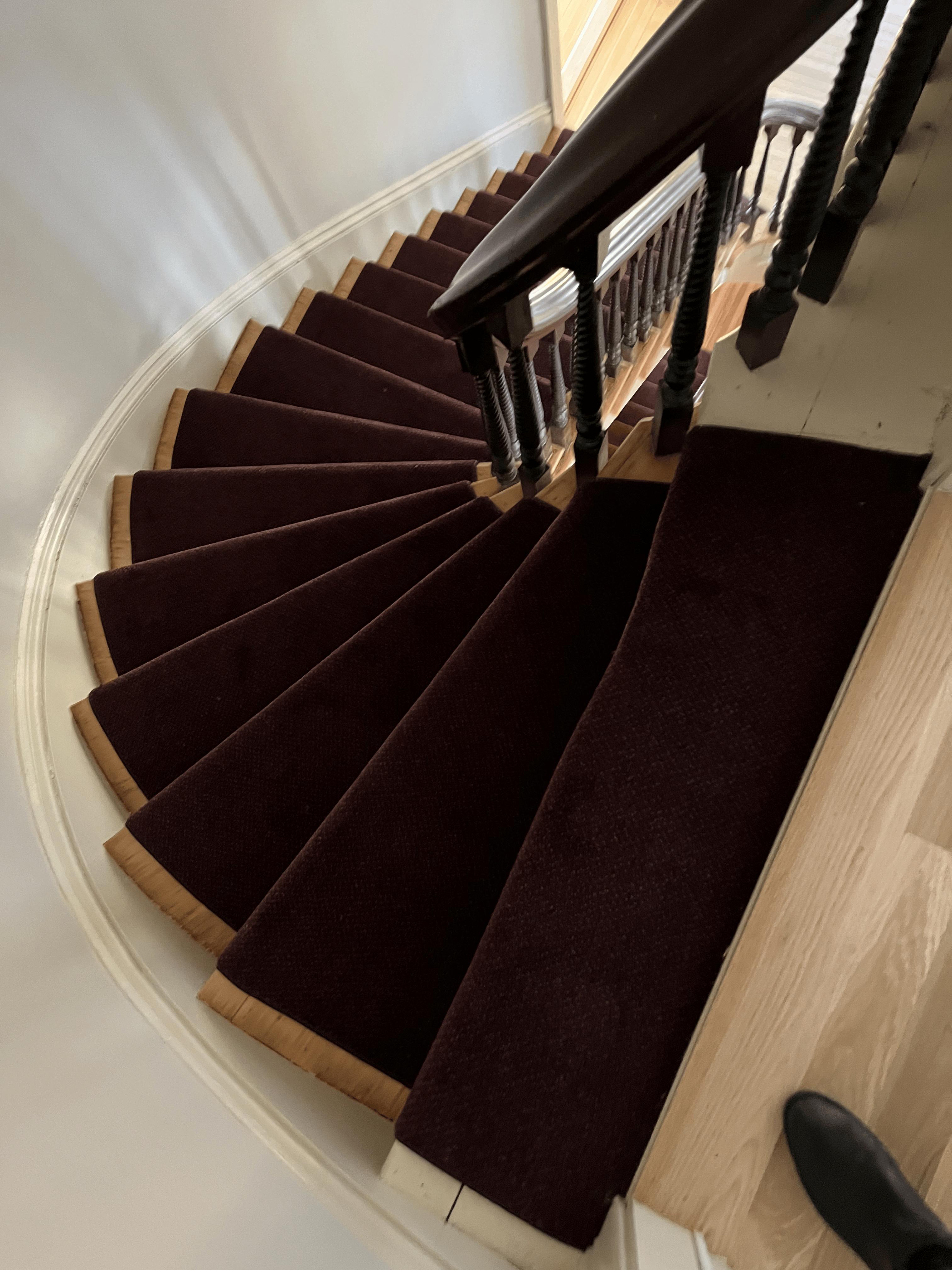 Deep burgundy carpet runner on a curved winding staircase