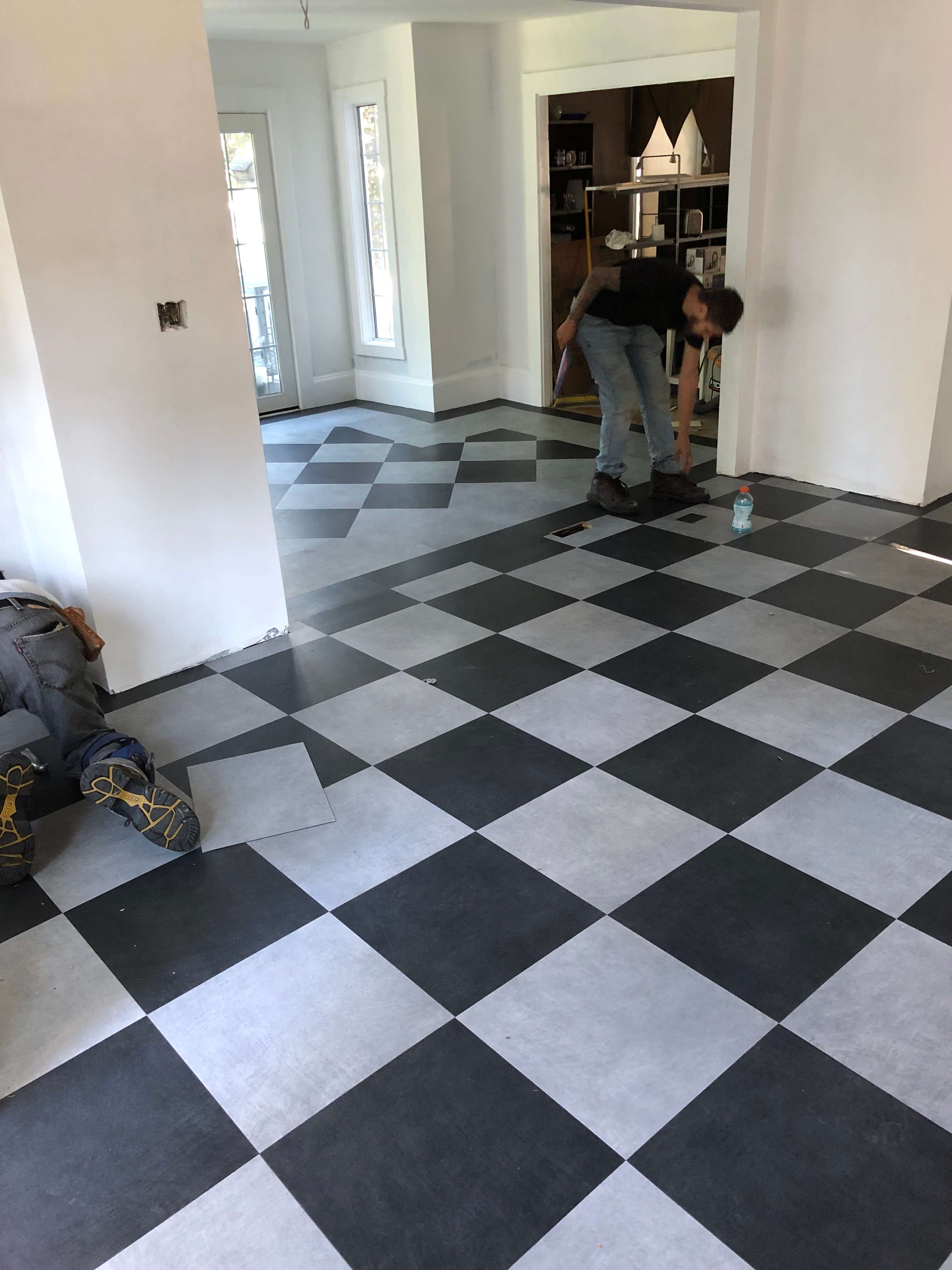 Black and white checkerboard VCT tile floor being installed in a home