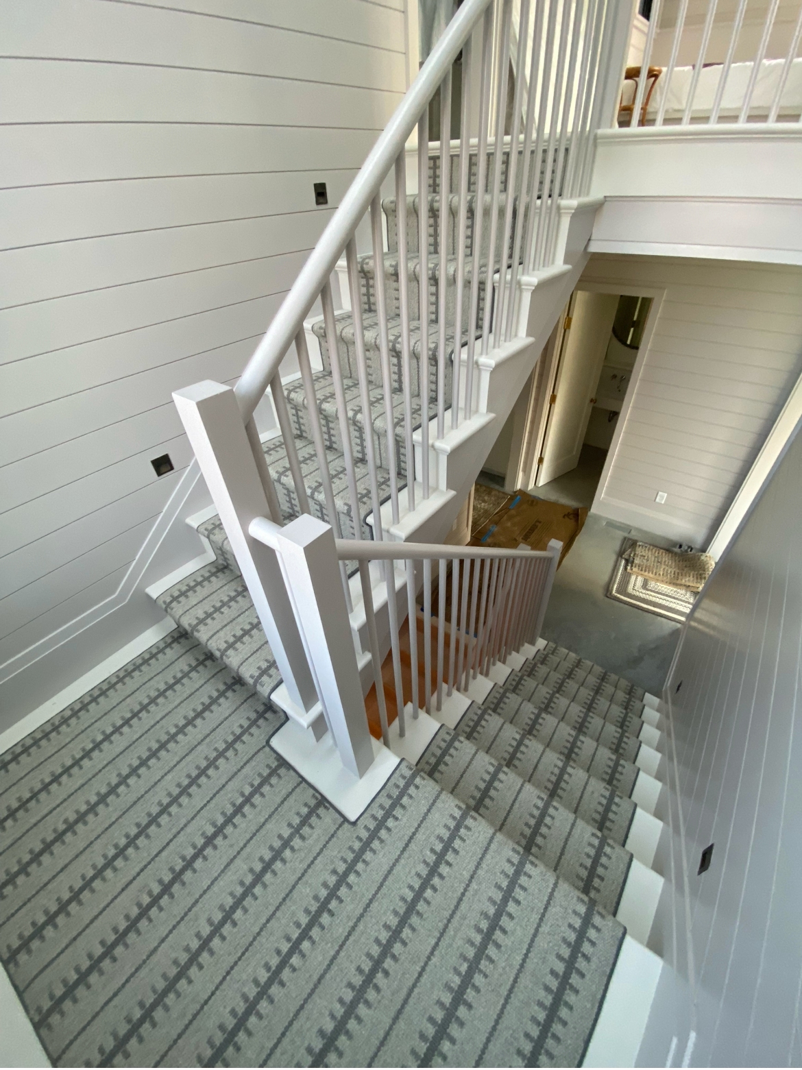 Gray ladder-stripe wool runner on a curved coastal staircase with shiplap walls