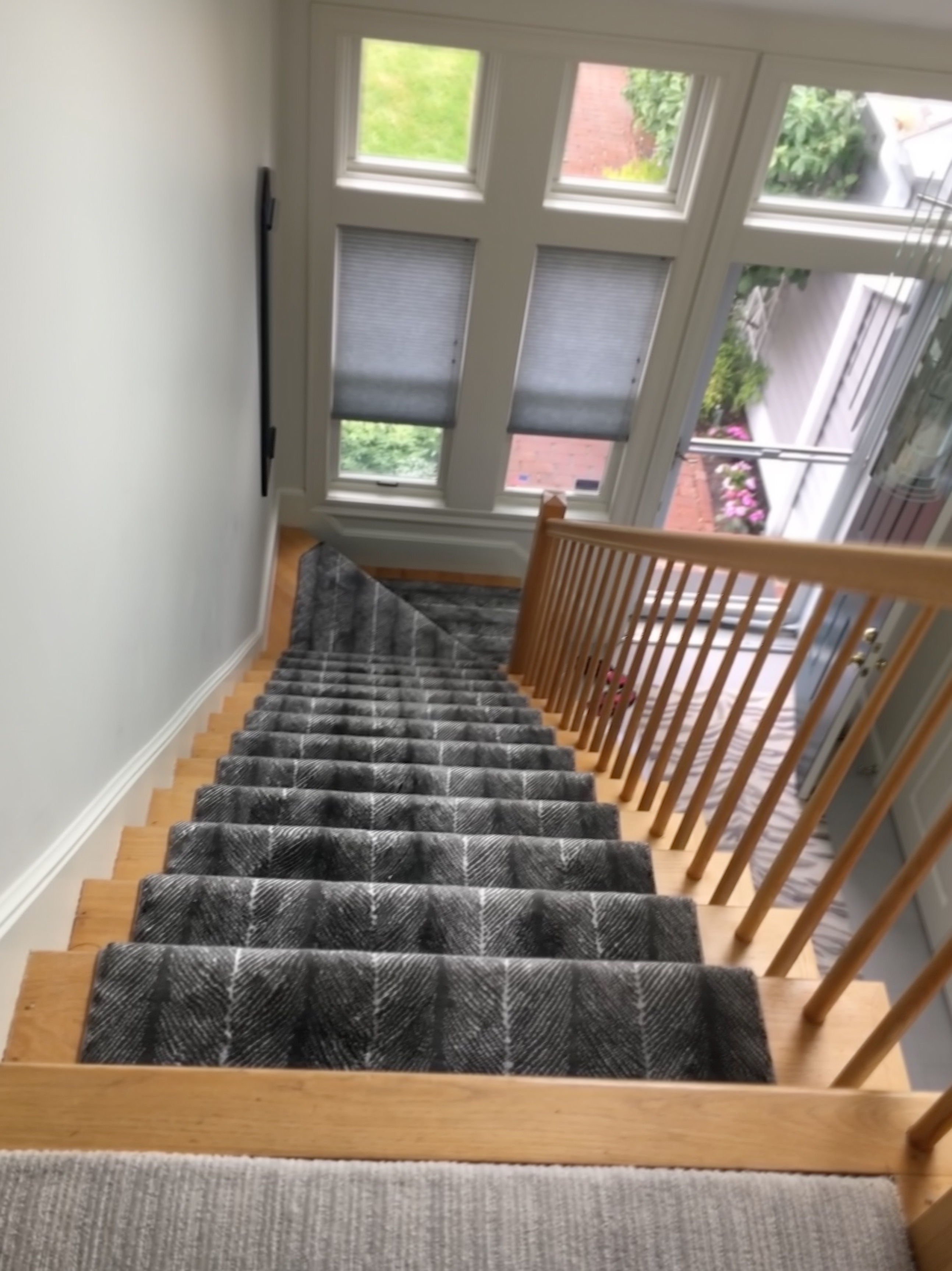 Gray herringbone stair runner descending toward a bright window landing
