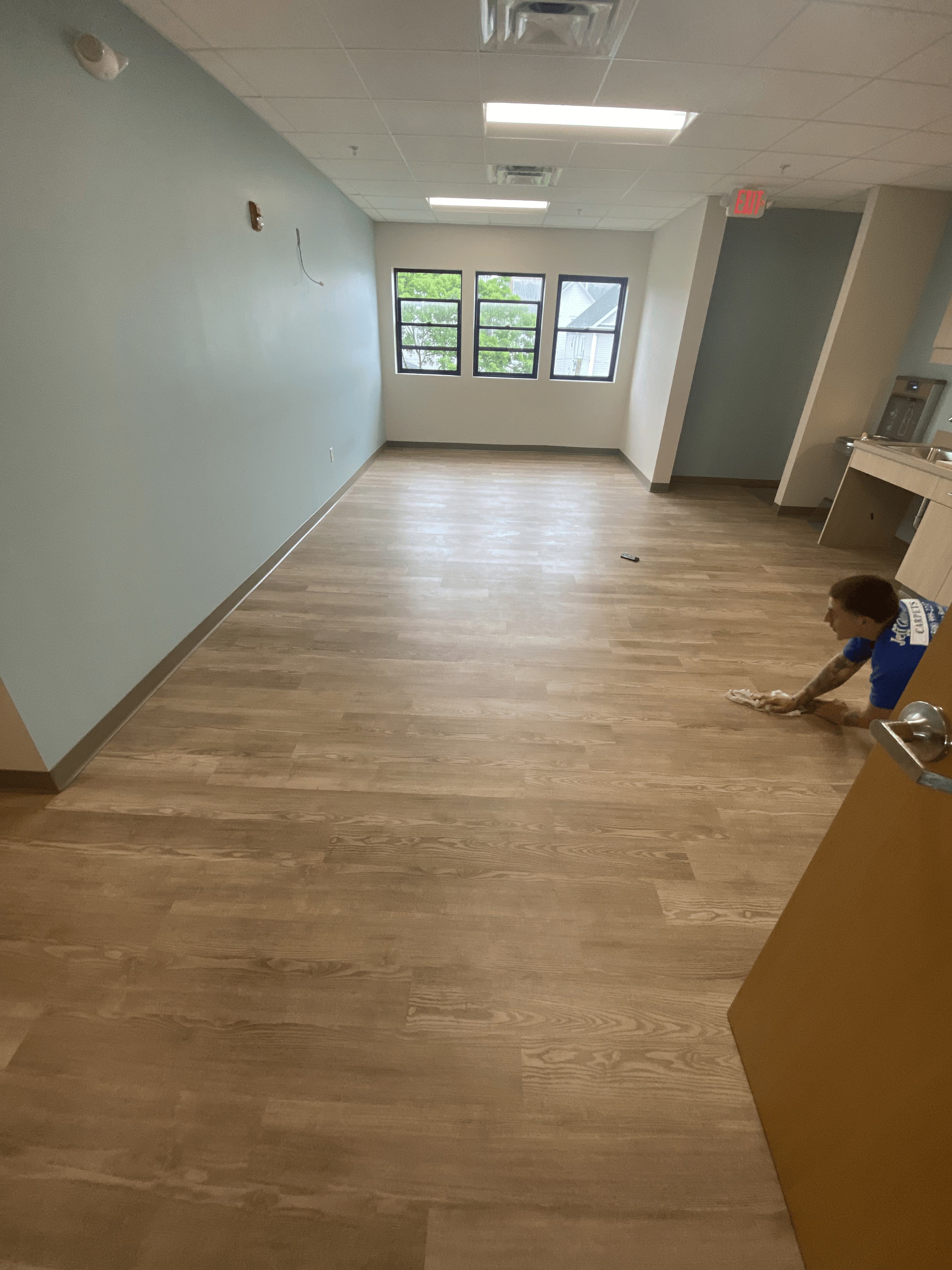 Installer finishing light wood-look luxury vinyl plank in an office