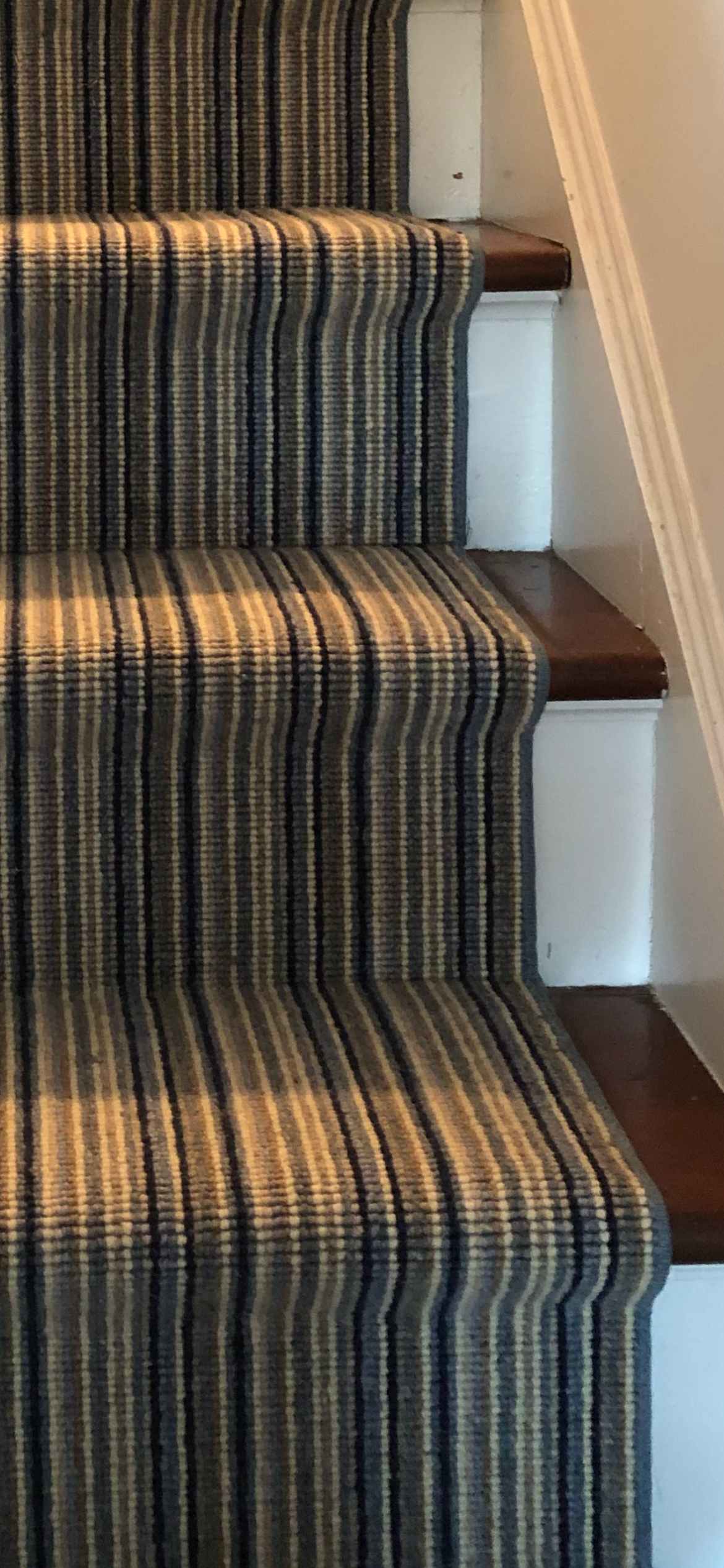 Close-up of a blue and tan pinstripe wool runner on dark stained treads
