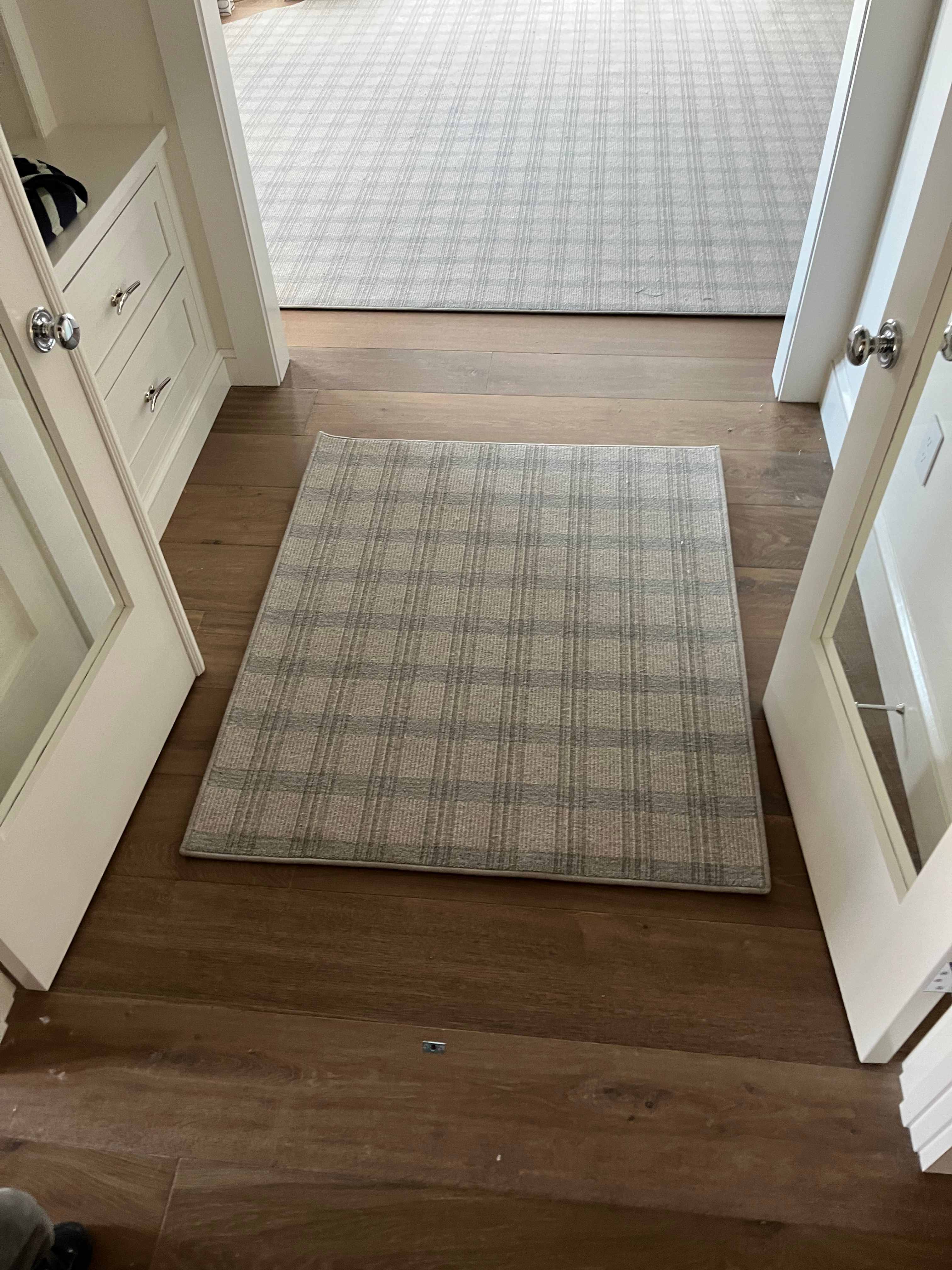 Plaid patterned carpet with a matching bound area rug over hardwood