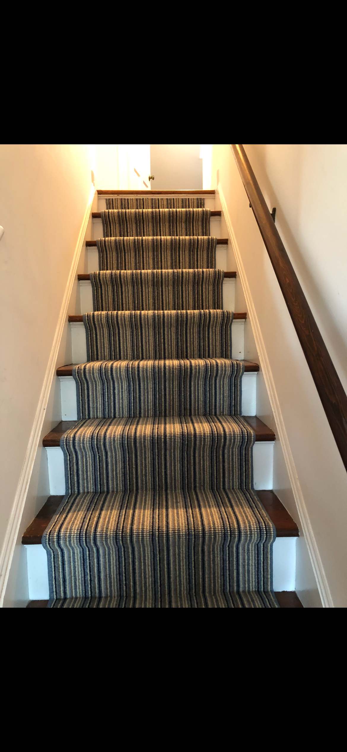 Blue and tan striped stair runner on a straight staircase with dark treads